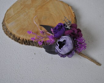 Op de afbeelding: Een klein boeket van paarse en roze kunstbloemen met een jute steel. De bloemen zijn gerangschikt op een houten schijf.