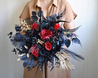 Puede incluir: Un ramo de novia negro y rojo con plumas negras, detalles dorados y rosas rojas.