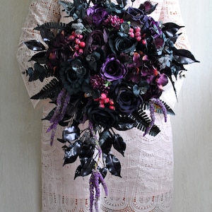 May include: A dark purple and black bridal bouquet with cascading purple flowers and black leaves.