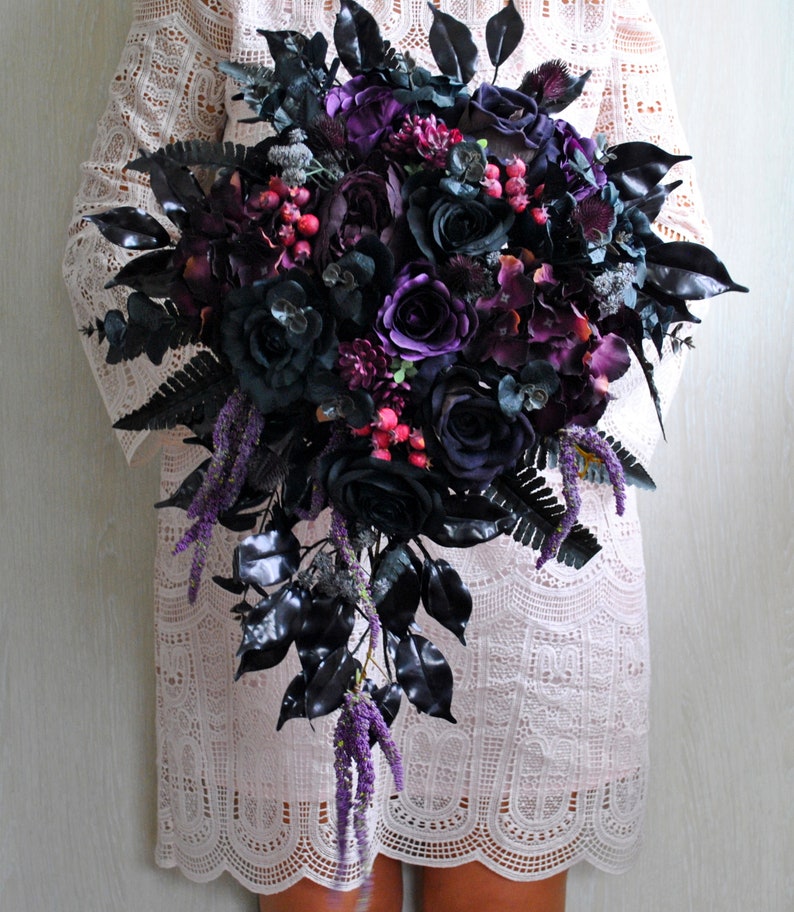 May include: A dark purple and black bridal bouquet with cascading purple flowers and black leaves.