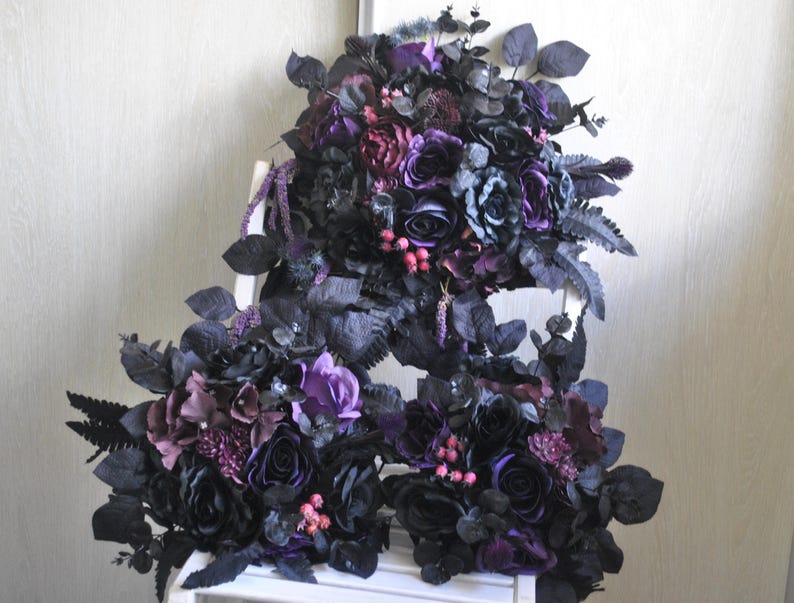 May include: Three bouquets of artificial flowers in shades of purple and black. The bouquets are made of silk flowers and greenery and are arranged in a cascading style.