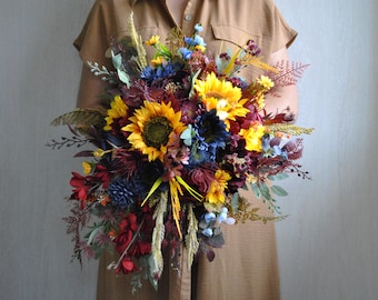 May include: A vibrant autumnal bridal bouquet featuring sunflowers, burgundy and blue flowers, and wheat stalks.
