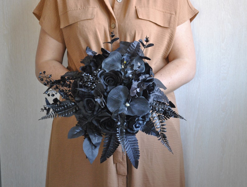 May include: A black wedding bouquet with roses, ferns, and other foliage.