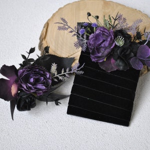 May include: Two black velvet hair clips with purple and black floral embellishments. The flowers are made of silk and have a vintage look.