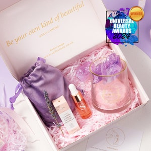 May include: A gift box containing a purple velvet drawstring pouch, a glass tumbler with raw purple crystals, a small bottle of essential oil, a sprig of dried lavender, and a card. The box lid features the text Be your own kind of beautiful.