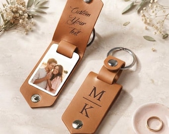 May include: Two tan leather keychains with silver metal snaps and rings. One keychain is open, revealing a rectangular photo of a couple and the engraved text Custom Your Text. The other keychain is closed, featuring the engraved letters M and K.