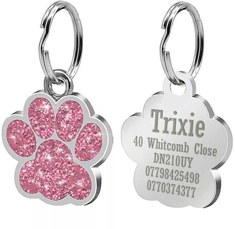 May include: Pink glitter paw print dog tag with silver ring and engraved text: Trixie, 40 Whitcomb Close, DN210UY, 07798425498, 0770374377.