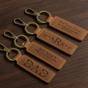 May include: Five brown leather keychains with gold metal rings. The keychains have different engraved text, including "Best Friends Forever", "Mummy", "Dad", and "ARS".