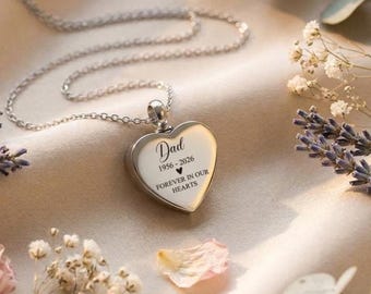 May include: A silver-toned heart-shaped pendant necklace featuring an engraved inscription that reads Dad, 1956-2026, a small heart symbol, and the text FOREVER IN OUR HEARTS. The pendant hangs from a delicate silver-toned metal chain.
