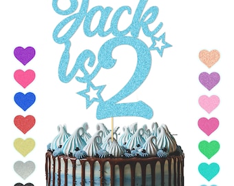Könnte beinhalten: Blauer Glitzer-Kuchentopper mit dem Namen "Jack" und der Zahl "2" mit Sternen. Der Topper befindet sich auf einem Schokoladenkuchen mit blauer Glasur.