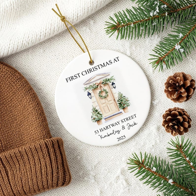 Puede incluir: Adorno navide&ntilde;o de cer&aacute;mica blanca con el texto &laquo;&nbsp;FIRST CHRISTMAS AT&nbsp;&raquo; y una ilustraci&oacute;n de acuarela de una puerta principal. El adorno tambi&eacute;n incluye la direcci&oacute;n &laquo;&nbsp;53 HARTWAY STREET&nbsp;&raquo; y los nombres &laquo;&nbsp;Kimberley & Jack&nbsp;&raquo; con el a&ntilde;o &laquo;&nbsp;2025&nbsp;&raquo;.