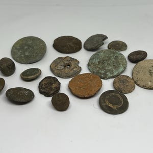 May include: A collection of 14 vintage metal buttons in various shapes, sizes, and colors, including brown, green, and silver.