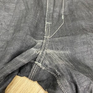 Peut inclure: Gros plan sur la couture d'un jean en denim gris fonc&eacute;. Les coutures sont blanches et le tissu est us&eacute;.