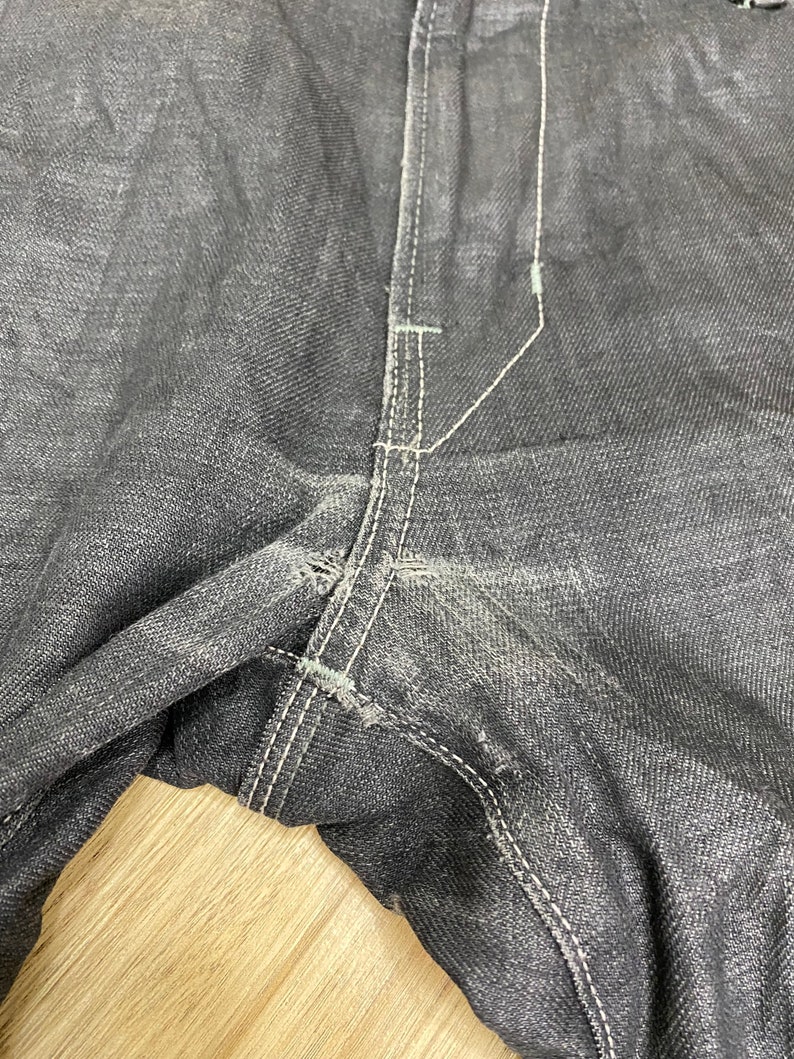 Peut inclure: Gros plan sur la couture d'un jean en denim gris fonc&eacute;. Les coutures sont blanches et le tissu est us&eacute;.