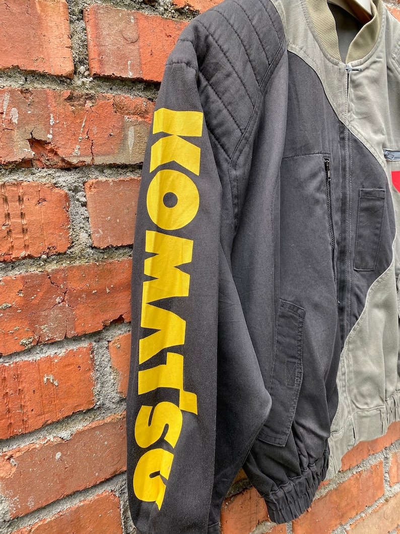 May include: Black and green bomber jacket with a yellow "DSQUARED2" logo on the left sleeve. The jacket has a zipper closure and a ribbed collar.