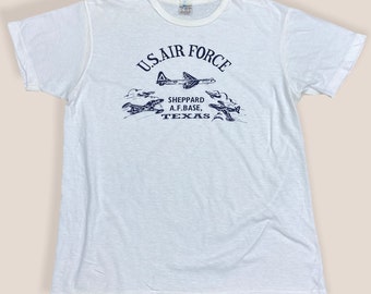 May include: White t-shirt with a blue print of aeroplanes and the text "U.S. AIR FORCE SHEPPARD A.F. BASE, TEXAS"