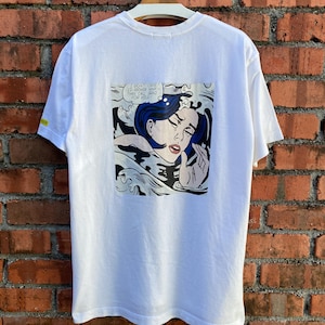 May include: White t-shirt featuring a pop art comic strip on the back. The artwork depicts a crying woman with blue hair in a body of water, with the text "I DON'T CARE! I'D RATHER SINK THAN CALL BRAD FOR HELP!"