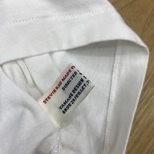 May include: White t-shirt with a white tag that says "Stevie Kai Made With Love", "Directed By Yamane Design", and "8 Rue 29 Juillet 75011 Paris".