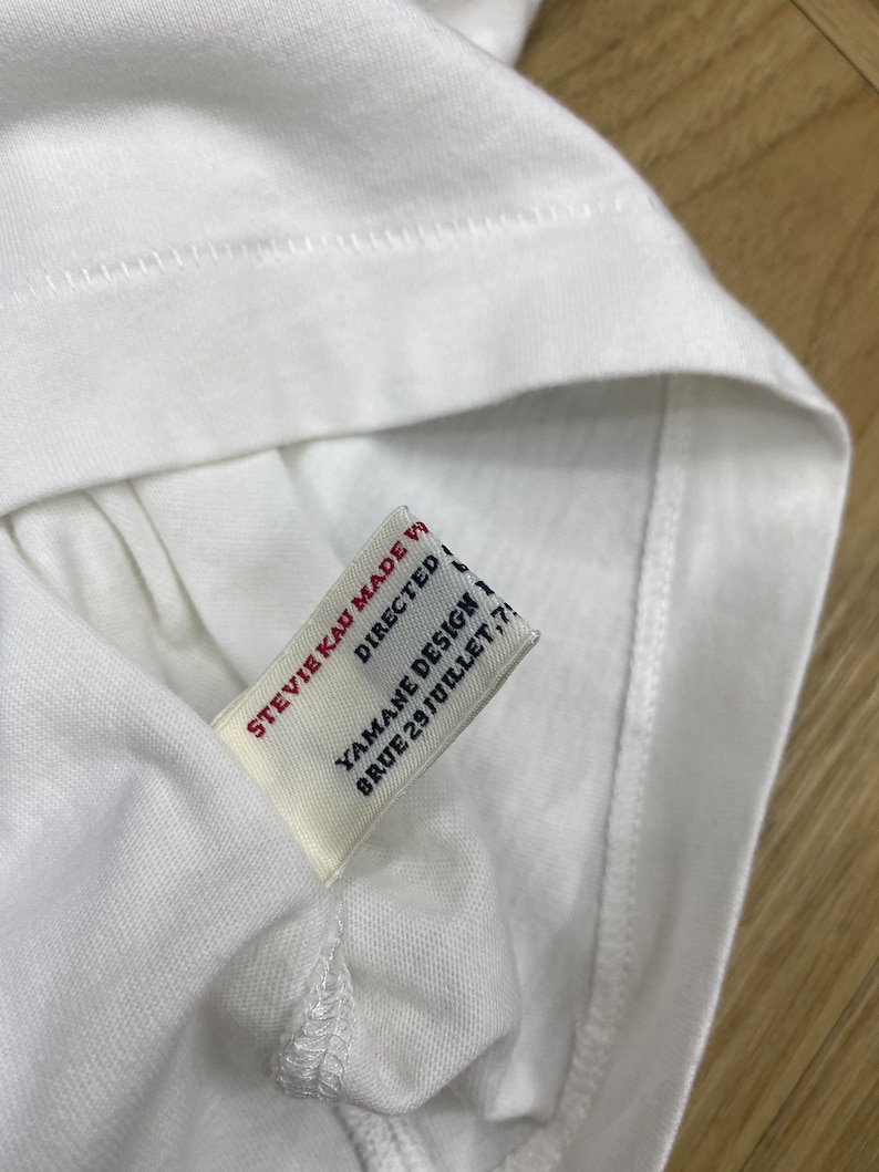 May include: White t-shirt with a white tag that says "Stevie Kai Made With Love", "Directed By Yamane Design", and "8 Rue 29 Juillet 75011 Paris".