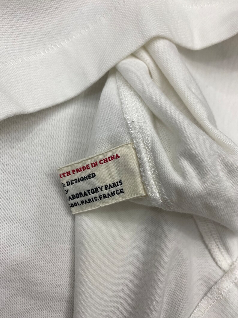 May include: White clothing tag with red text that reads "With pride in China" and "Designed by Laboratory Paris 1001 Paris, France".