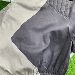 May include: A black and gray bomber jacket with a quilted design on the sleeves and a contrasting gray panel on the back.
