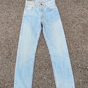 May include: Light blue denim jeans with a straight leg fit. The jeans have a classic five-pocket style and a button fly.