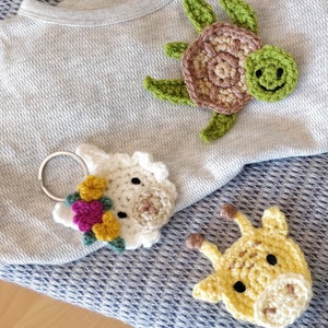 Peut inclure: Porte-clés en crochet en forme d'animaux, dont une tortue, un lama et une girafe. Les porte-clés sont faits de fil coloré et ont un aspect artisanal et fantaisiste.