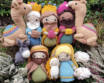 May include: A collection of crocheted nativity figures, including a camel, donkey, sheep, and three wise men. The figures are all dressed in colorful clothing and have detailed facial features.