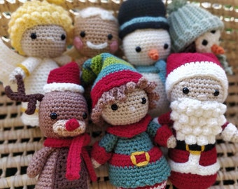 May include: A collection of crocheted Christmas decorations, including a reindeer, elf, Santa Claus, gingerbread person, angel, and snowman. The decorations are all made with different coloured yarn and have various details, such as a red scarf, a green hat, and a white beard.