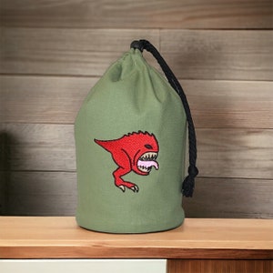 Peut inclure: Un sac à cordon vert avec un monstre rouge brodé sur le devant. Le monstre a une langue rose qui sort.