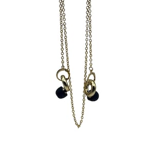 May include: A gold chain necklace with two black charms. The charms are made of multiple interlocking rings.