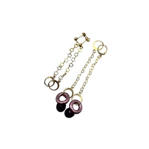 May include: A pair of gold earrings with a star chain and a purple bead and ring dangle.
