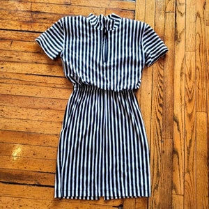 May include: A black and white striped short-sleeved dress with a mock neck and a zipper closure.