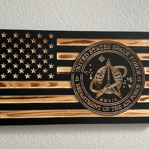 May include: A wooden American flag with a black background and a gold seal in the center. The seal reads "United States Space Force Department of the Air Force MMXIX".