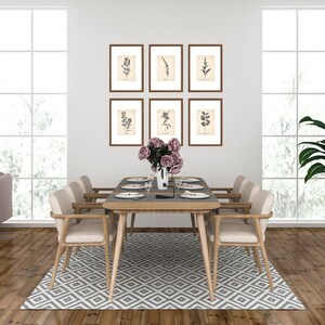 K&ouml;nnte beinhalten: Ein Esstisch mit sechs St&uuml;hlen, einem Teppich und einer Vase mit rosa Blumen. Der Tisch ist mit Tellern, Besteck und Gl&auml;sern gedeckt. An der Wand h&auml;ngen gerahmte botanische Drucke.