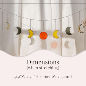 Puede incluir: Colgante decorativo con lunas y un sol de vidrieras en tonos amarillo, naranja y gris. La pieza est&aacute; suspendida de una cadena y mide aproximadamente 76 cm de ancho x 13 cm de alto cuando se estira.