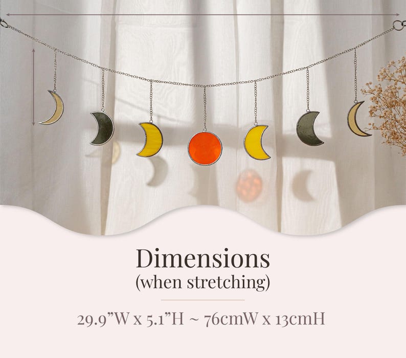 Puede incluir: Colgante decorativo con lunas y un sol de vidrieras en tonos amarillo, naranja y gris. La pieza est&aacute; suspendida de una cadena y mide aproximadamente 76 cm de ancho x 13 cm de alto cuando se estira.