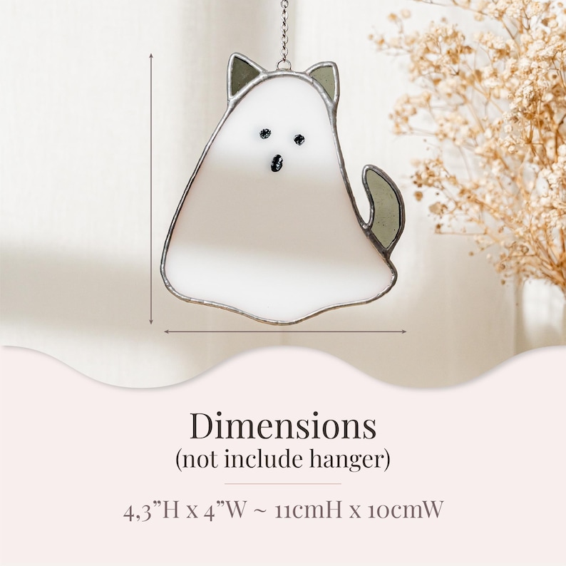 May include: A stained glass cat-shaped suncatcher with a white body, gray ears, and tail. The cat has black eyes and a mouth. The dimensions are 4.3 inches high by 4 inches wide. It hangs from a silver chain.