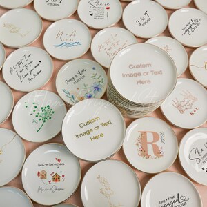 May include: A collection of round white ceramic plates with gold-trimmed edges, featuring various personalized designs including floral patterns, calligraphy, dates, and the placeholder text Custom Image or Text Here in gold or black ink.