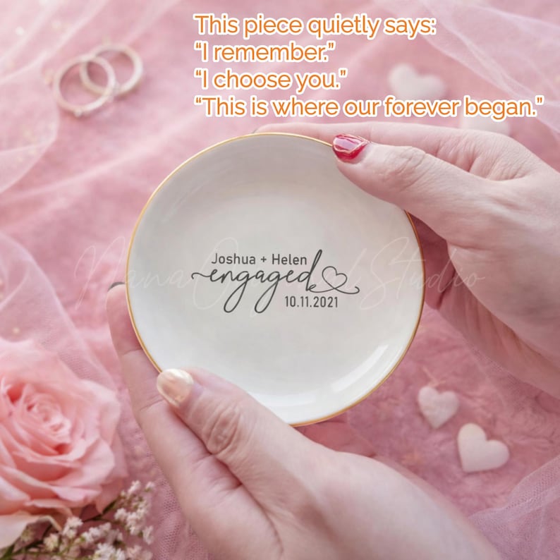 May include: A white ceramic ring dish with a gold rim, featuring the word "engaged" and the names "Joshua + Helen" along with the date "10.11.2021". The dish has text that reads "I remember", "I choose you", and "This is where our forever began."