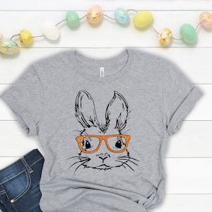 May include: A gray t-shirt with a black and white illustration of a bunny wearing orange glasses.