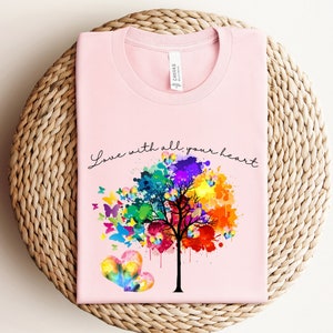 May include: Pink t-shirt with a colorful tree and butterflies, and the text "Love with all your heart".