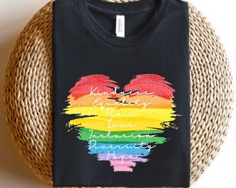 May include: Black t-shirt with a rainbow heart design. The heart has the words "Kindness", "Equality", "Peace", "Love", "Inclusion", "Diversity", and "Hope" written on it.