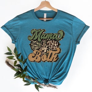May include: Teal blue t-shirt with a graphic design that says "Mama of Both" in a retro font. The graphic features camouflage and leopard print sunglasses.