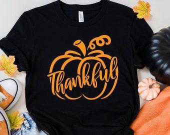 May include: Black t-shirt with an orange pumpkin graphic and the word "thankful" written inside the pumpkin.
