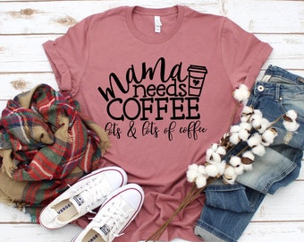 May include: A mauve t-shirt with the text "mama needs coffee lots & lots of coffee" in black lettering. A coffee cup icon is next to the word "coffee".