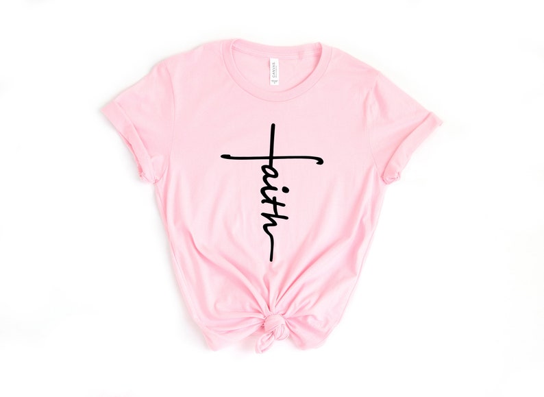 May include: A pink t-shirt with a black cross and the word "faith" written vertically down the cross.