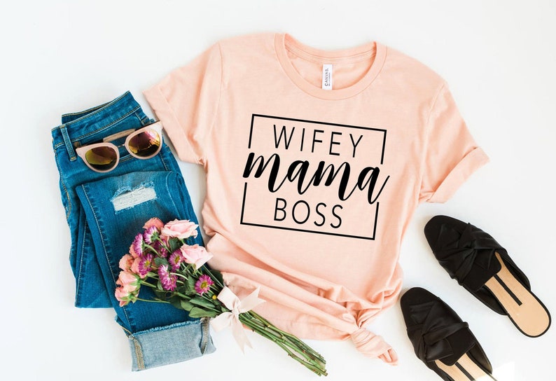 May include: A peach-colored t-shirt with the text "WIFEY mama BOSS" printed in black inside a black square.