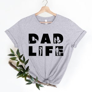 May include: A grey t-shirt with the text "DAD LIFE" in black. The letters are made up of silhouettes of a father interacting with his children.