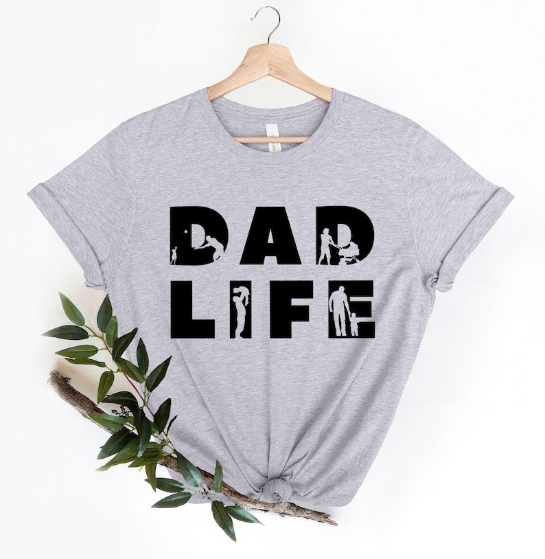 May include: A grey t-shirt with the text "DAD LIFE" in black. The letters are made up of silhouettes of a father interacting with his children.
